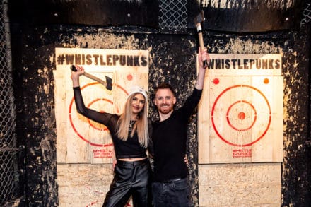 a woman and a man holding axes with target on their backroundd
